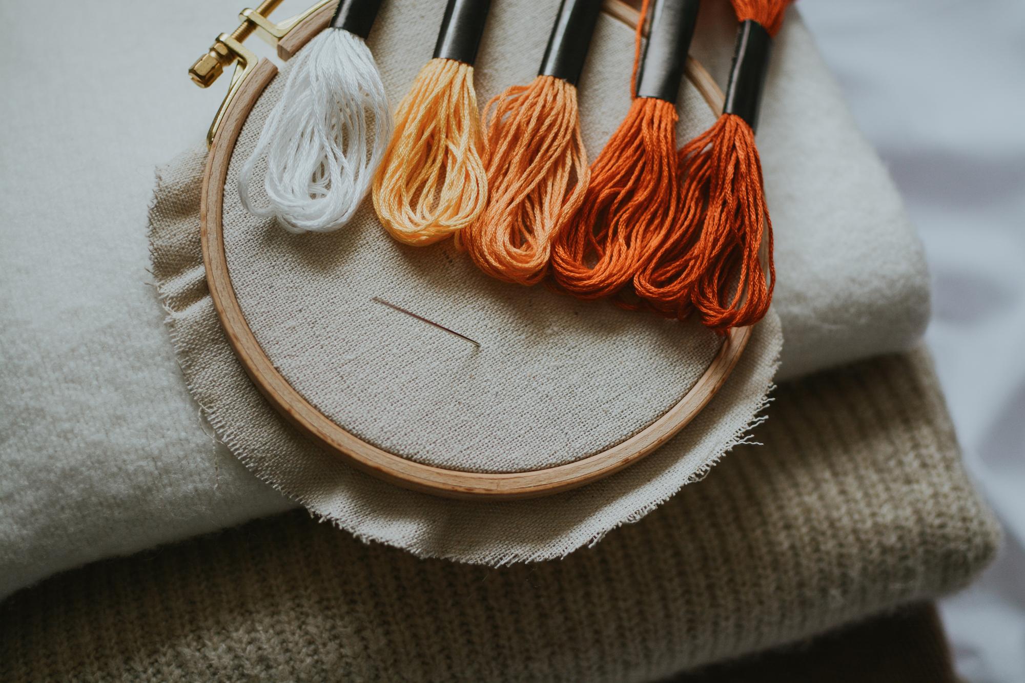 Close-up of hand embroidery on linen with pastel threads